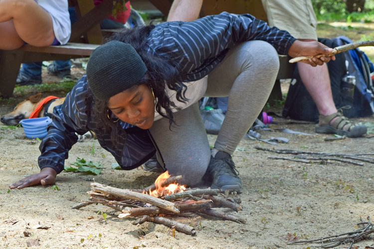 A counselor successfully lighting her first campfire!
