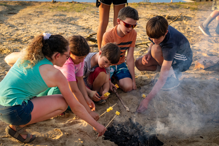 Roasting pineapple on skewers over a beach campfire