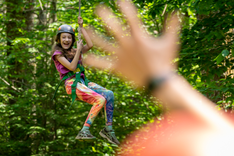 A camper enjoying the zipline on our ropes course