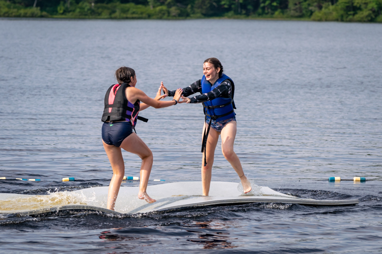 Two campers in PFDs playing on the Lily Pad