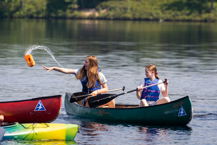 Playing a game in the kayaks and canoes involving a wet sponge and a lot of laughter