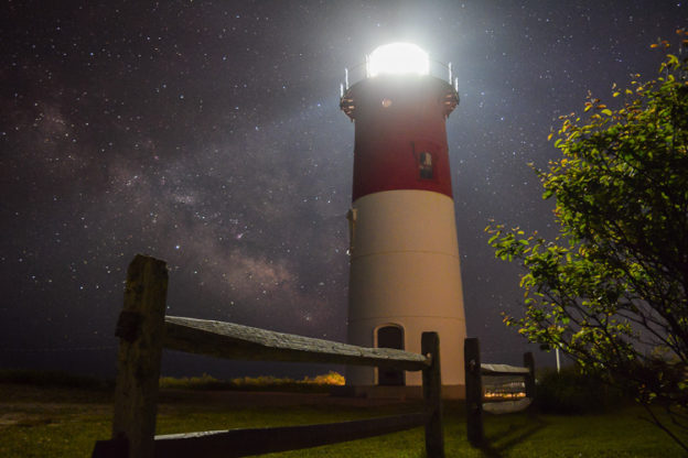 Starry sky behind an illuminated lighthouse