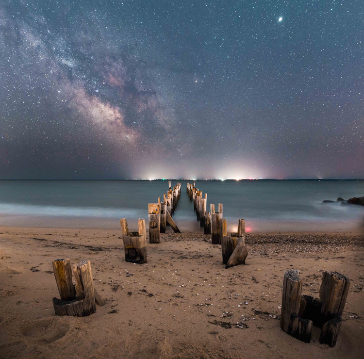 Starry sky over an old jetty on the beach