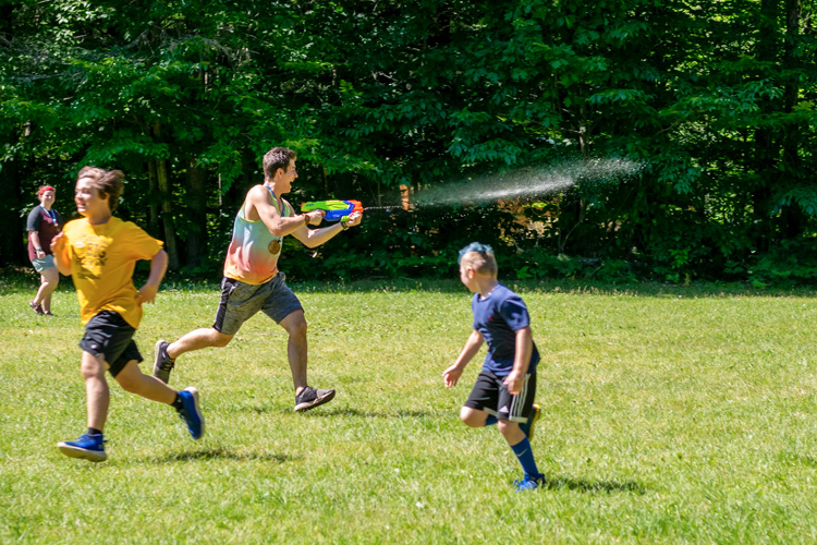 Jackson Lieb playing a game of tag with campers on a hot day using a super soaker