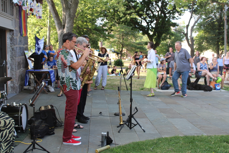 A band playing outside the Powder Building with people looking on and dancing. 