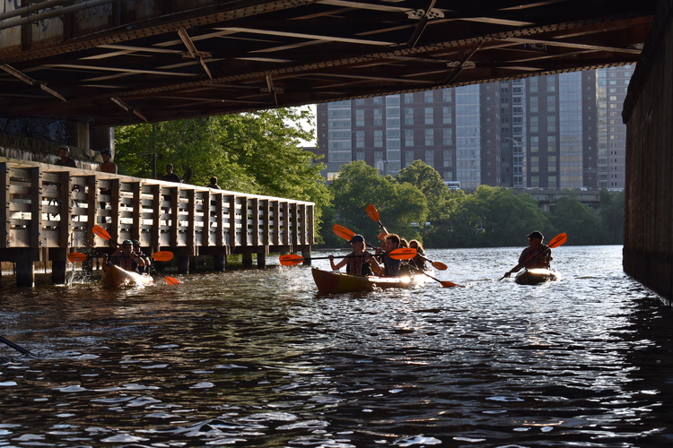 Kayakers pass beneath a bridge on the Charles River.